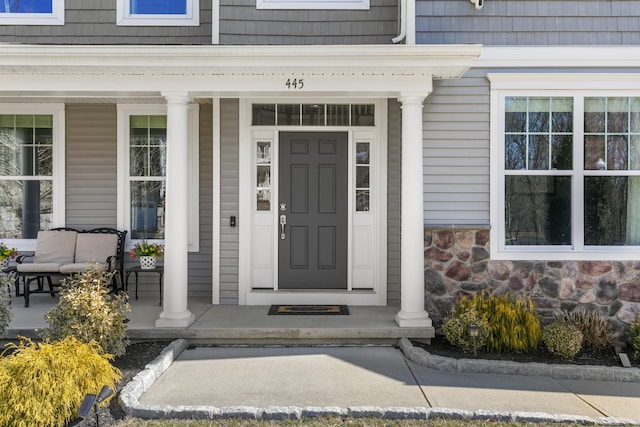 doorway to property with stone siding and a porch