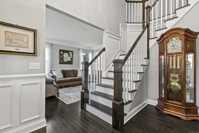 staircase with baseboards, ornamental molding, a decorative wall, and hardwood / wood-style floors