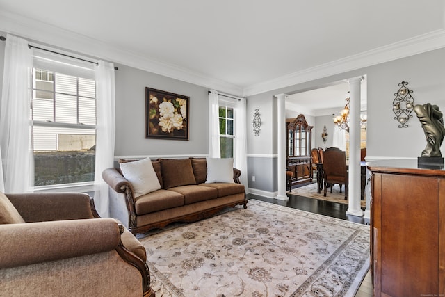 living area featuring ornamental molding, a notable chandelier, ornate columns, and wood finished floors