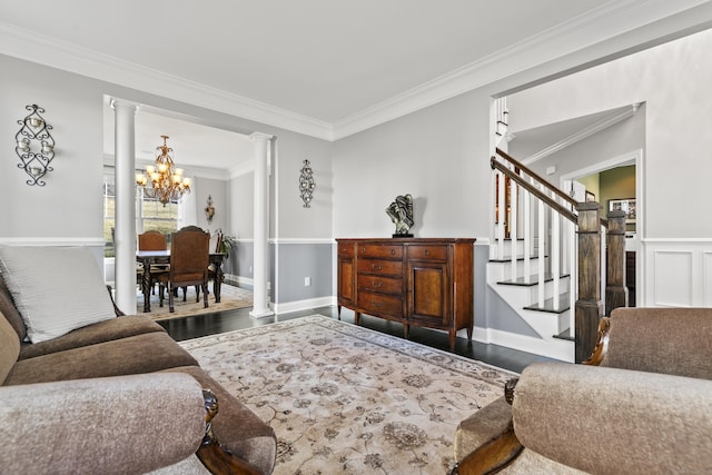 living room featuring ornamental molding, wood finished floors, stairs, ornate columns, and a notable chandelier