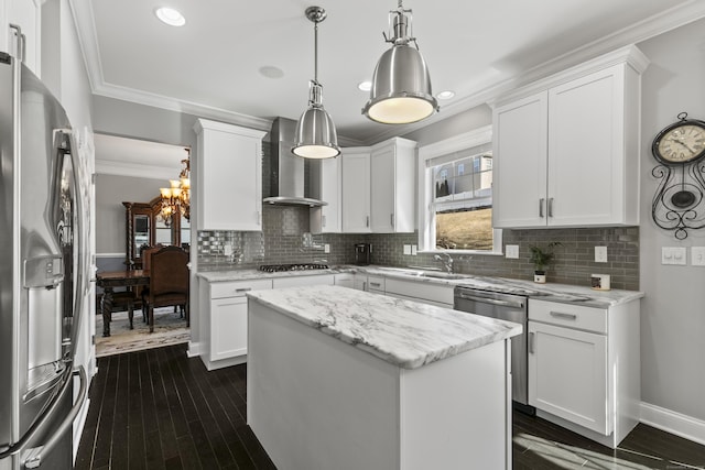 kitchen with ornamental molding, appliances with stainless steel finishes, wall chimney range hood, and white cabinets