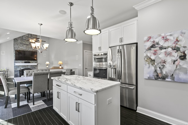 kitchen with a fireplace, a kitchen island, white cabinetry, appliances with stainless steel finishes, and decorative light fixtures