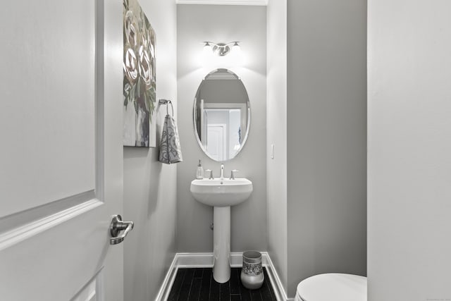 half bathroom with baseboards and toilet