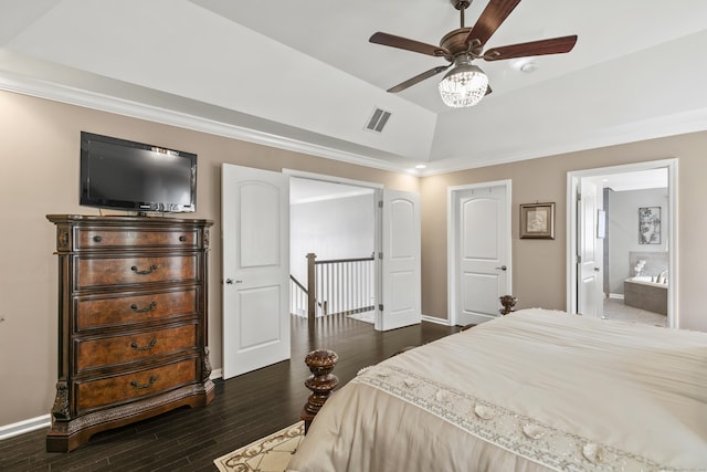 bedroom with baseboards, visible vents, a raised ceiling, dark wood-style floors, and ensuite bath