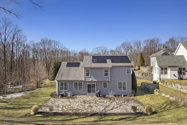 back of property featuring a yard, a patio, fence, and solar panels