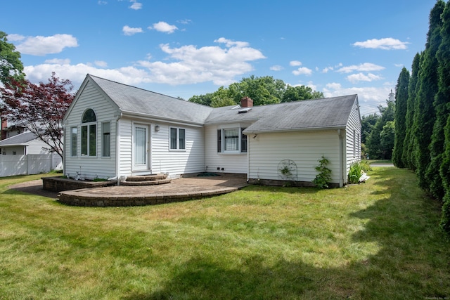 rear view of property featuring a patio, a yard, a chimney, and fence