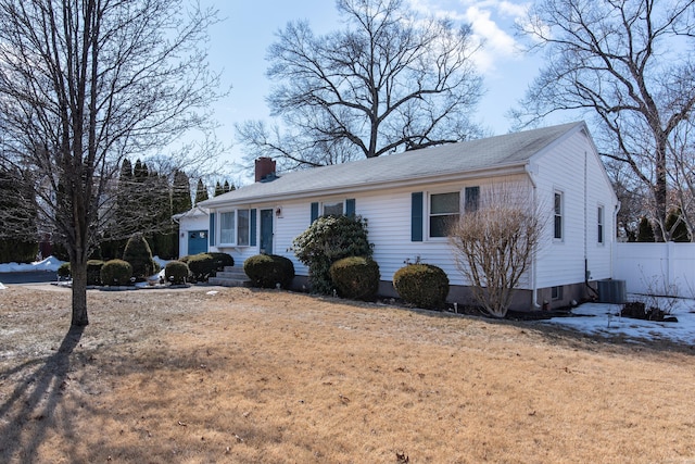 ranch-style home featuring entry steps, a chimney, fence, and central AC unit