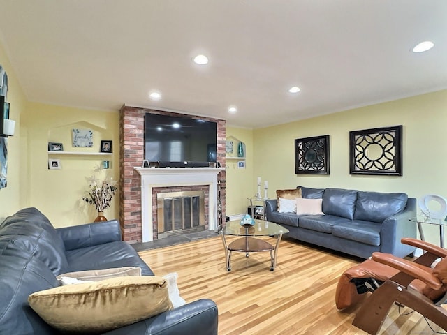 living room with a brick fireplace, wood finished floors, and recessed lighting