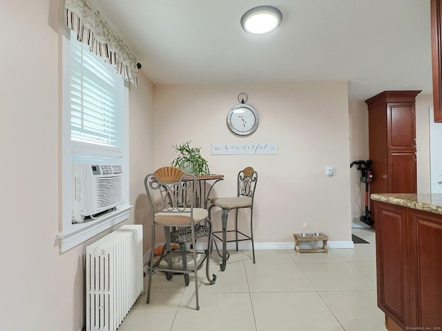 dining space featuring light tile patterned floors, baseboards, cooling unit, and radiator