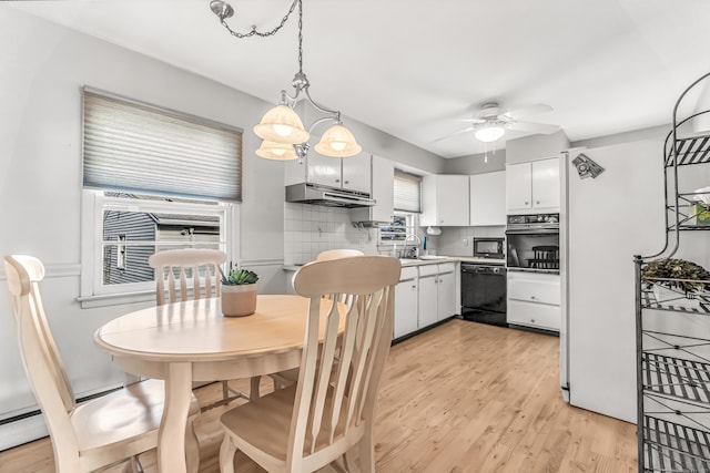 kitchen with under cabinet range hood, light wood-type flooring, black appliances, white cabinetry, and backsplash