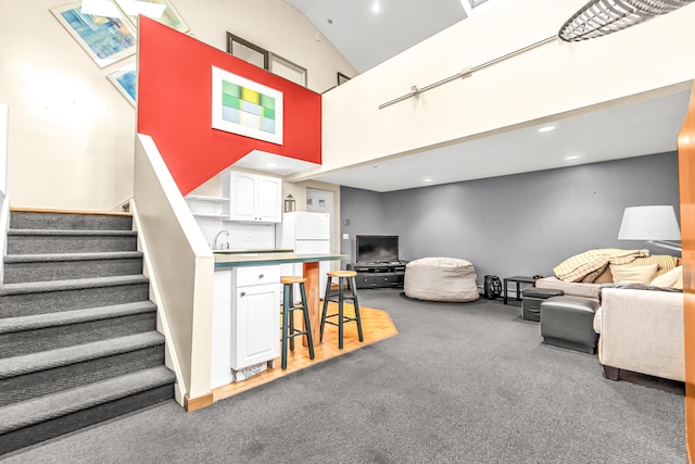 living area featuring high vaulted ceiling, recessed lighting, carpet floors, and stairway