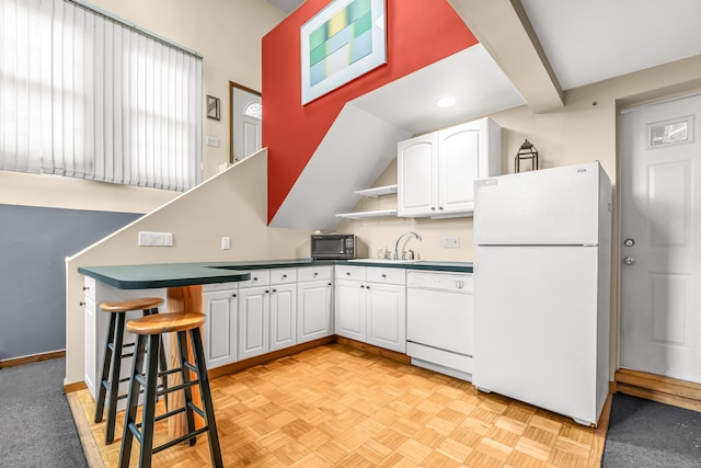 kitchen featuring a peninsula, white appliances, white cabinetry, and a breakfast bar area