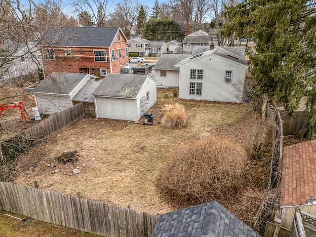 rear view of house featuring an outbuilding, a fenced backyard, a residential view, and a storage shed