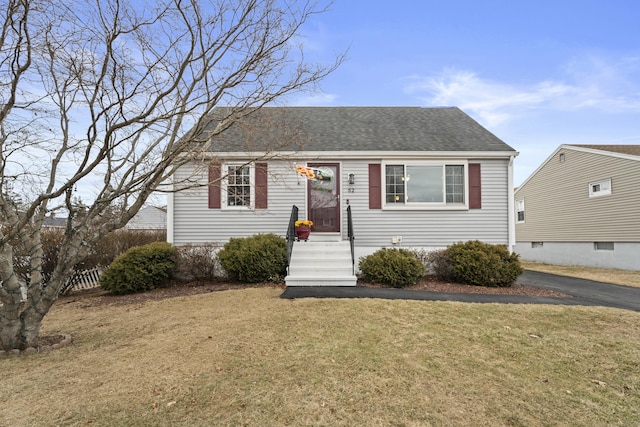 view of front of home featuring a shingled roof and a front yard