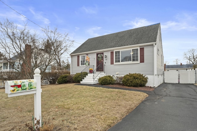 view of front of property featuring a front yard, roof with shingles, fence, and driveway