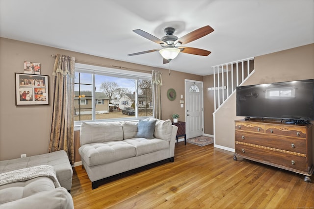 living area featuring ceiling fan, stairway, wood finished floors, and baseboards