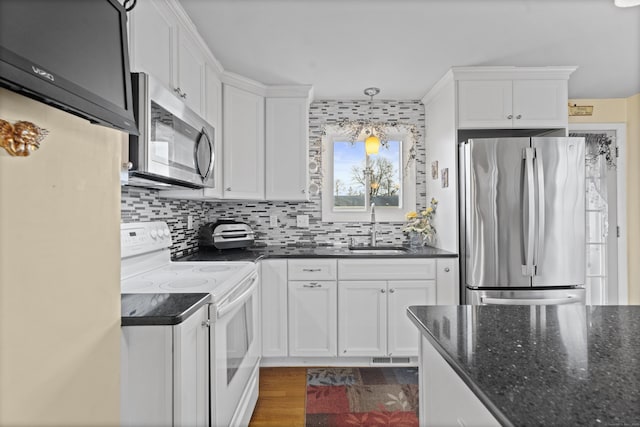 kitchen featuring stainless steel appliances, a sink, white cabinetry, decorative backsplash, and dark stone counters