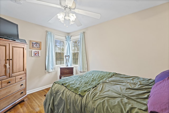 bedroom with light wood-style floors, baseboards, and a ceiling fan