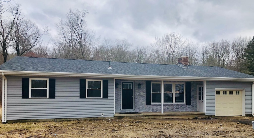 single story home featuring a garage, roof with shingles, brick siding, and a chimney