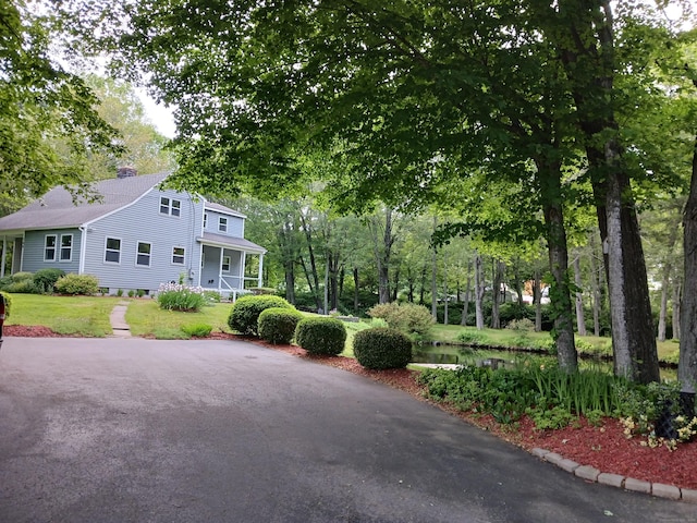 153 Bozrah St, Bozrah, CT 06334 - view of front of property with a chimney, a porch, a front lawn, a shingled roof, and view of scattered trees