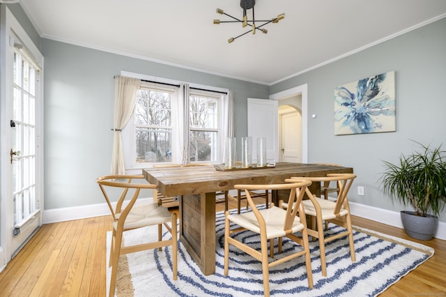 dining area featuring arched walkways, light wood finished floors, crown molding, and baseboards