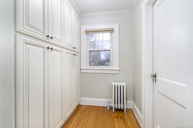 interior space with crown molding, baseboards, radiator heating unit, and light wood-style floors