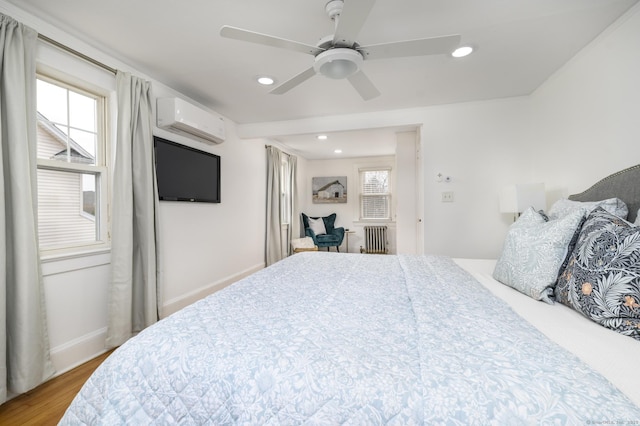 bedroom with a wall mounted air conditioner, wood finished floors, recessed lighting, radiator, and baseboards