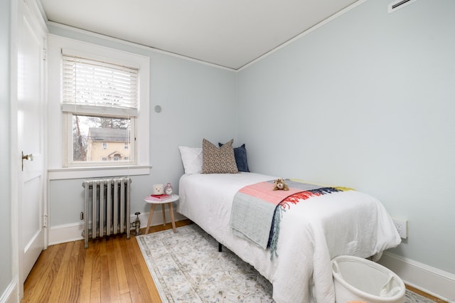 bedroom with baseboards, radiator, and hardwood / wood-style flooring