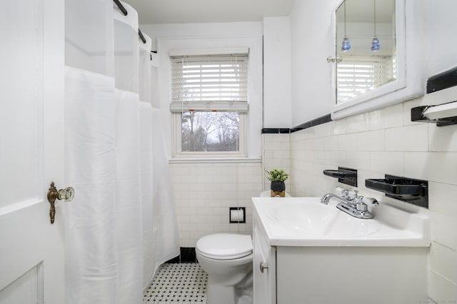 full bathroom featuring toilet, a shower with shower curtain, tile walls, wainscoting, and vanity