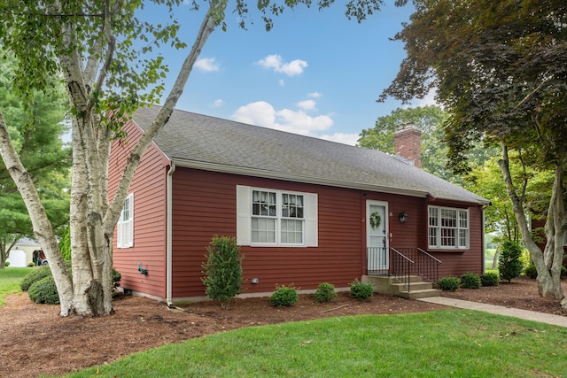 view of front facade featuring a chimney, a front lawn, and roof with shingles