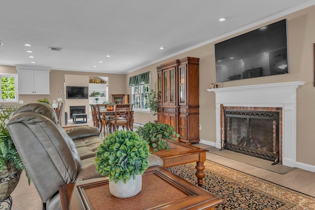 living room with recessed lighting, visible vents, a fireplace with flush hearth, ornamental molding, and baseboards