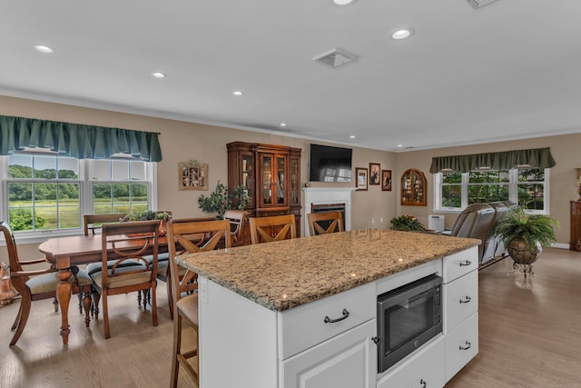 kitchen featuring plenty of natural light, a fireplace, light wood-style flooring, and built in microwave