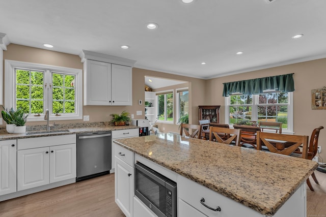 kitchen featuring a kitchen island, a sink, a wealth of natural light, built in microwave, and dishwasher