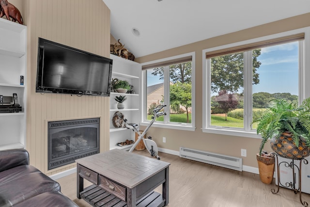 living room with light wood-style flooring, vaulted ceiling, baseboard heating, and a glass covered fireplace