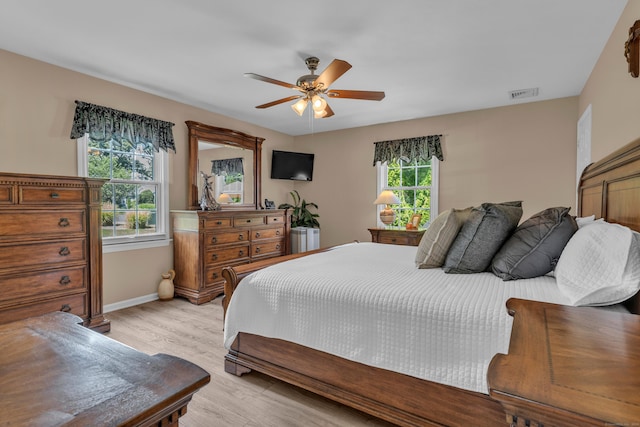 bedroom featuring a ceiling fan, visible vents, light wood-style flooring, and baseboards