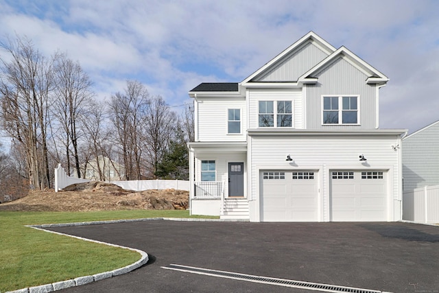 view of front of property with a porch, an attached garage, a front yard, fence, and driveway