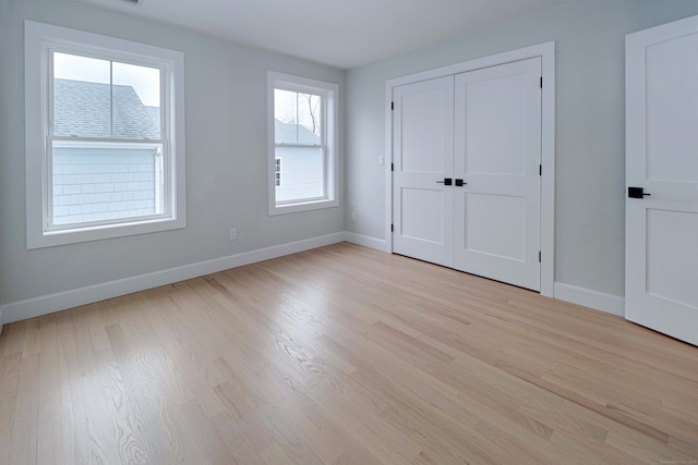 unfurnished bedroom with baseboards, a closet, and light wood-style floors