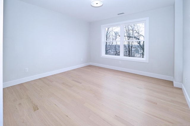 unfurnished room featuring light wood-style floors, visible vents, and baseboards