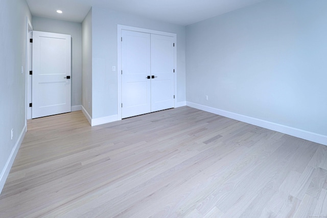 unfurnished bedroom with light wood-style floors, baseboards, and a closet