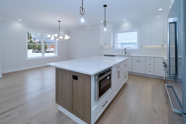 kitchen featuring crown molding, a wealth of natural light, light wood-type flooring, and a sink