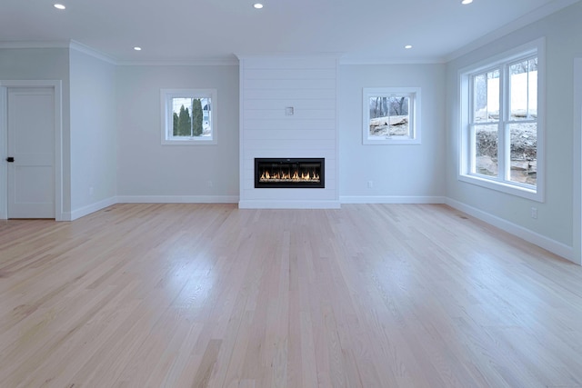 unfurnished living room with a large fireplace, baseboards, and ornamental molding