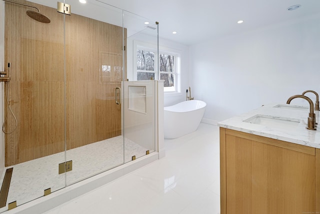 full bathroom featuring a stall shower, a freestanding tub, a sink, and recessed lighting