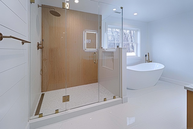 full bath with baseboards, a freestanding tub, a shower stall, and recessed lighting