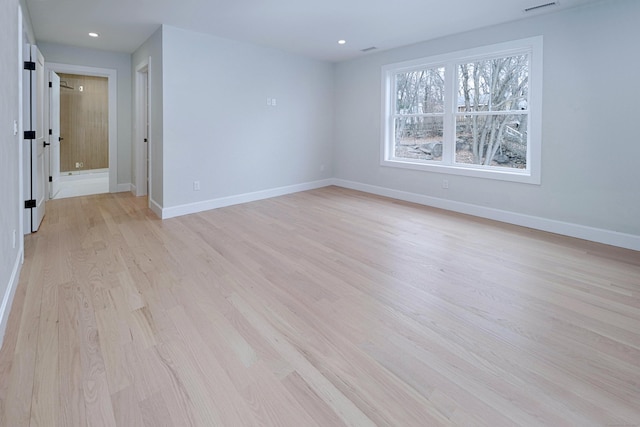 empty room with light wood finished floors, recessed lighting, and baseboards