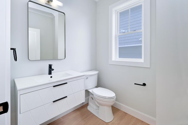 bathroom with vanity, wood finished floors, toilet, and baseboards