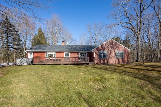 view of front of property featuring a deck, a chimney, and a front lawn