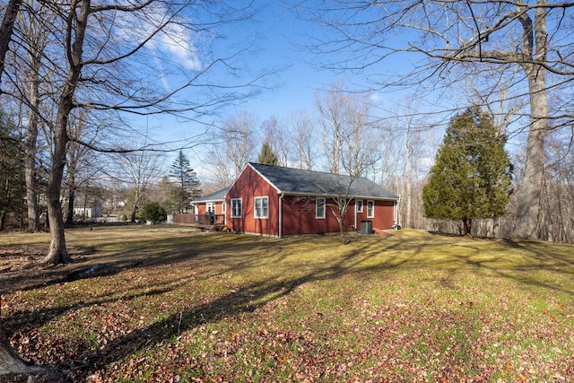 view of side of property with central AC unit, a lawn, and fence