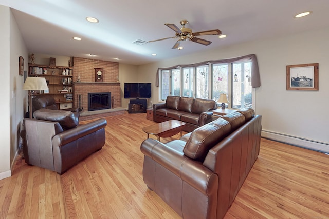 living area with a baseboard radiator, a brick fireplace, light wood-style flooring, and visible vents