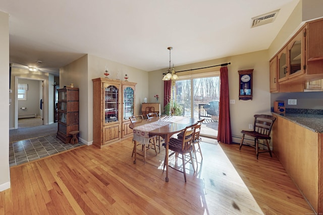 dining room with light wood finished floors, baseboard heating, and visible vents