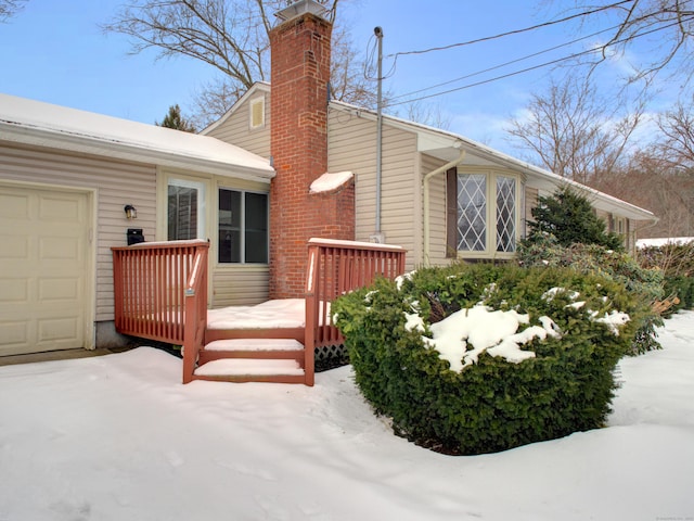 exterior space featuring a deck, a chimney, and an attached garage